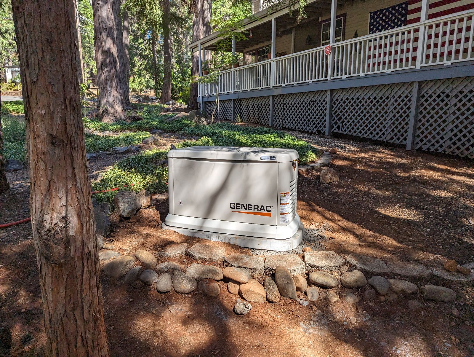 Generac standby generator installed on a concrete pad in a wooded residential yard.