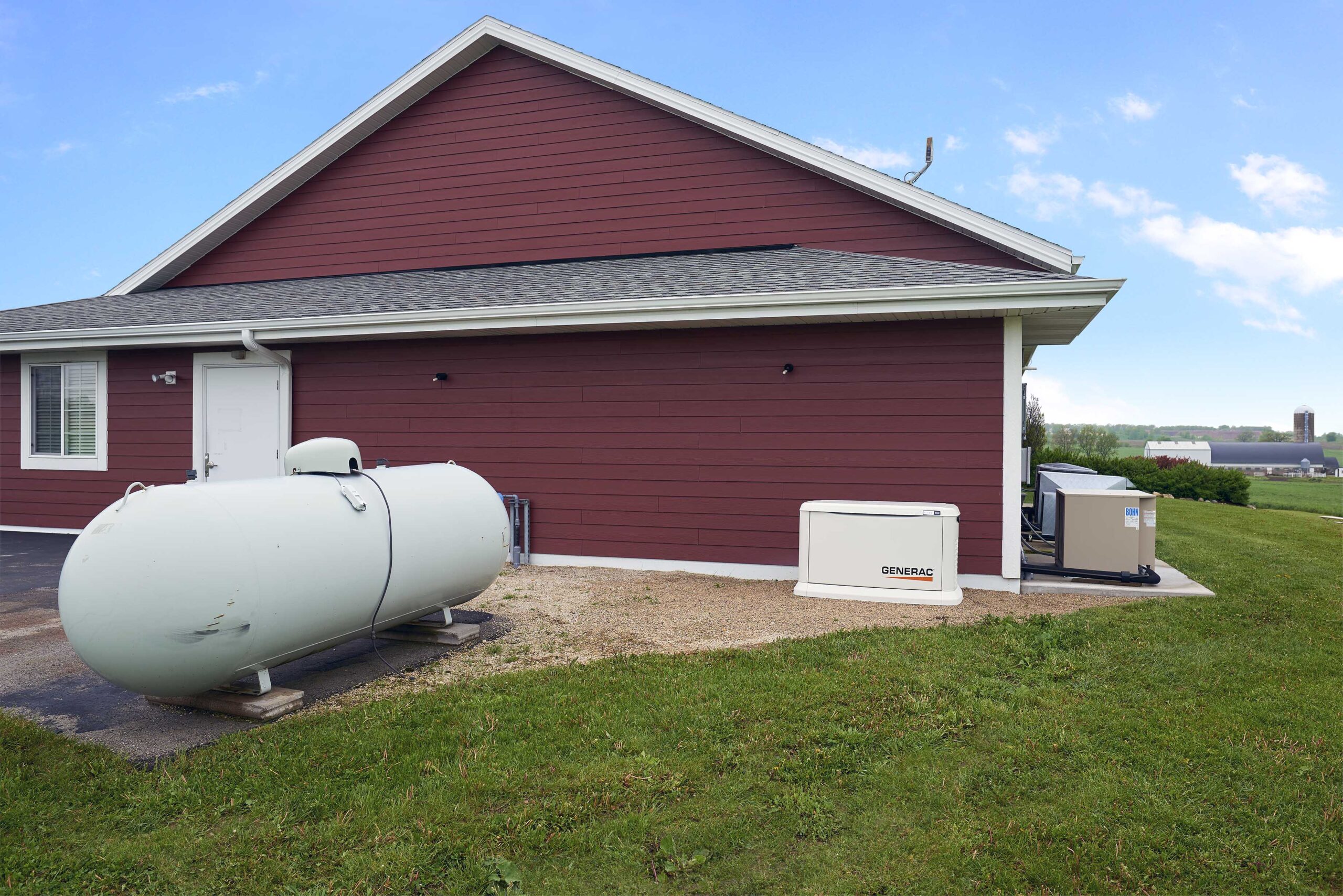 Generac standby generator installed beside a home with an on-site propane fuel tank.