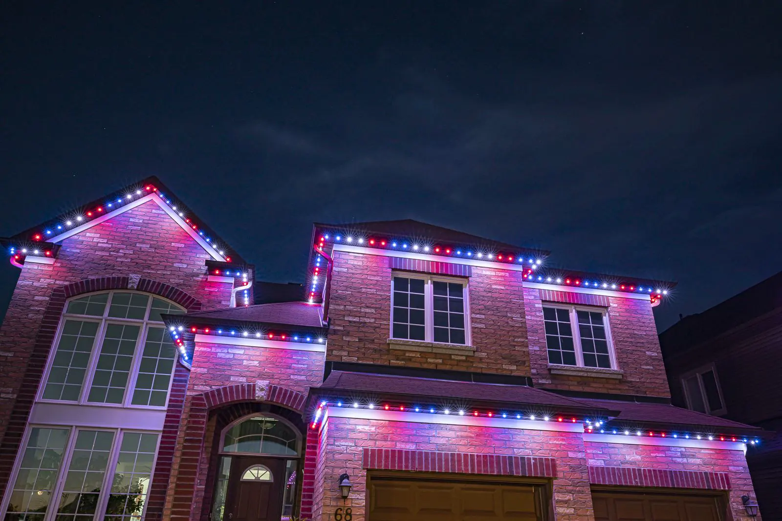 Stone and brick two-story home with red, white and blue permanent lighting